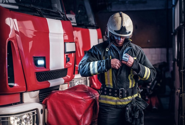 fireman clothes protective uniforms standing next to the fire engine in the garage of a fire department
