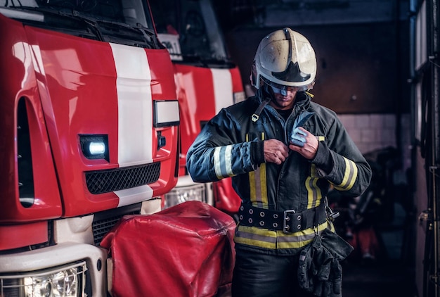 Fireman clothes protective uniforms standing next to the fire engine in the garage of a fire department