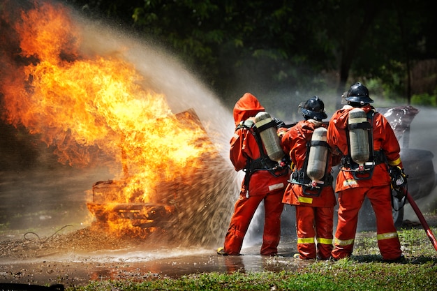 Foto vigili del fuoco che utilizzano estintore e acqua per il fuoco di combattente durante l'allenamento di lotta contro gli incendi.