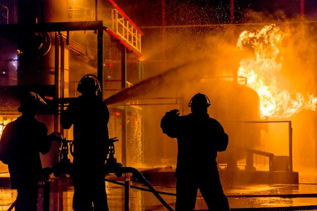 Firemen using water from hose for fire fighting at firefight training of insurance group