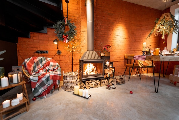 Fireplace area of a beautiful loft-style interior with real brick and concrete floors decorated for the New Year holidays. The concept of home comfort