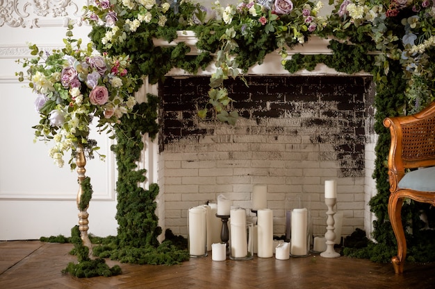 Fireplace  and candles. wedding decorated area. vintage  fireplace decorated with spring flowers, wreath, candles.brick wall.