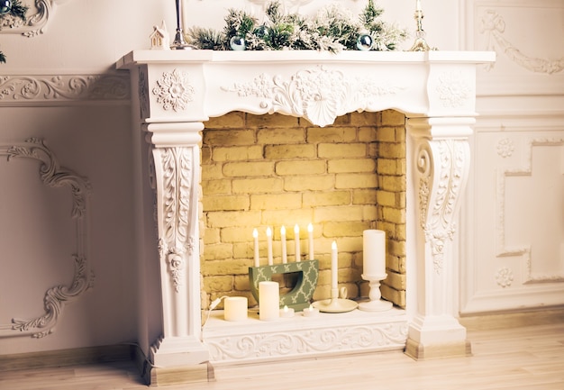 Fireplace with Christmas decor and candles on wooden floor