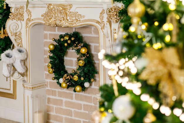 クリスマスツリーのトウヒの枝にモミの花輪のクリスマスのおもちゃのボールと花輪のある暖炉