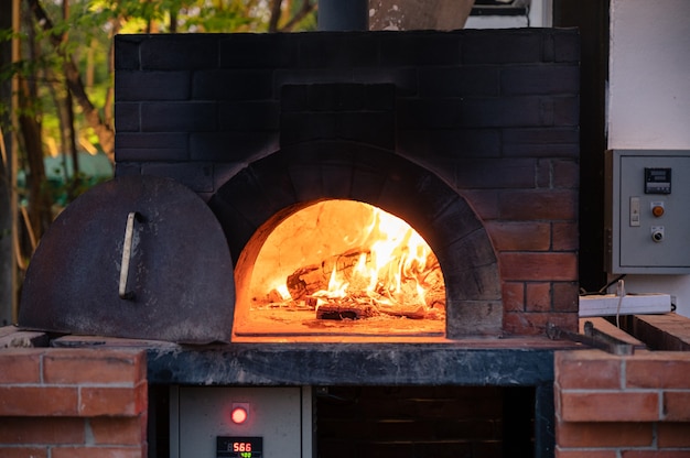 Photo firewood burning in traditional pizza stove at pizzeria