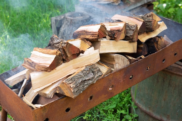 Firewood in the grill, the fire is burning and there is smoke. Open fire, burning wood