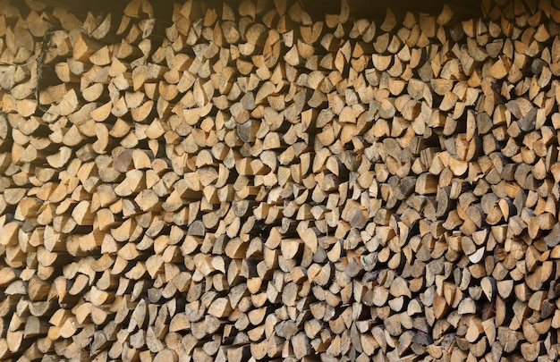 Firewood stacked near the wooden wall of old hut many chopped logs of firewood