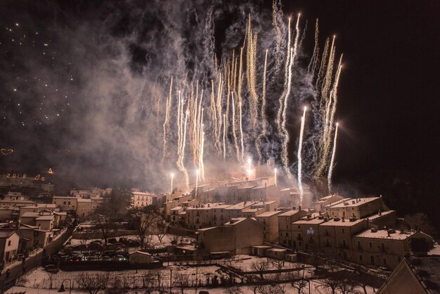 Photo firework display over houses against sky at night