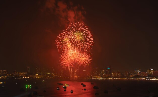 Firework display over illuminated city against sky at night