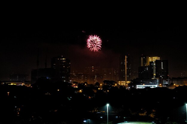 Firework display over illuminated city against sky at night