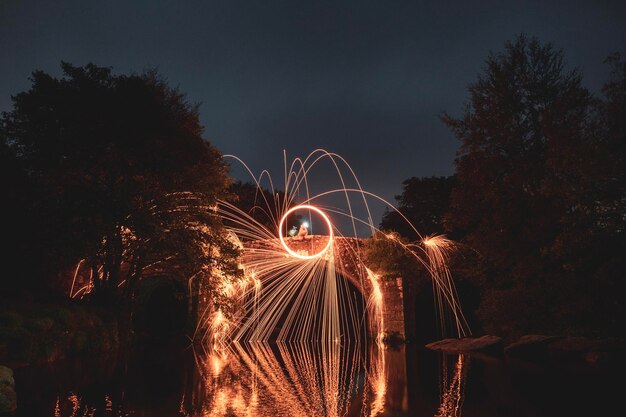 Firework display over lake against sky at night