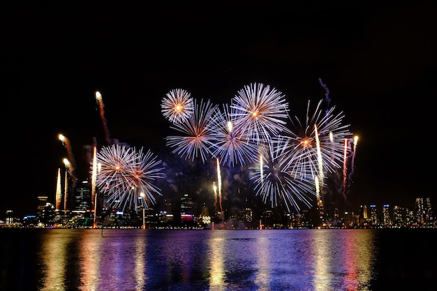 夜の河川と都市風景の上の花火