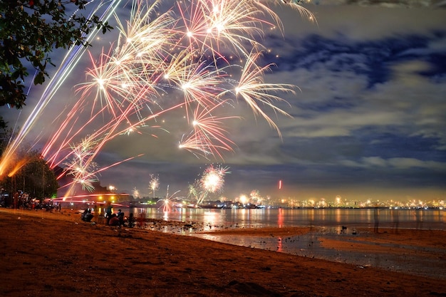firework display over sea against sky at night