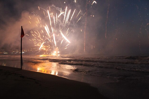 Photo firework display over sea at night