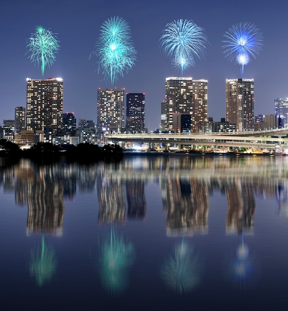 Fireworks celebrating over Tokyo cityscape with mirror reflection at nigh