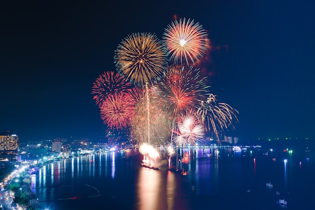 Foto fuochi d'artificio sul mare spiaggia con sfondo blu cielo crepuscolare e vista sulla città