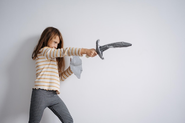 Firm standing girl posing with selfmade toy paper sword and shield