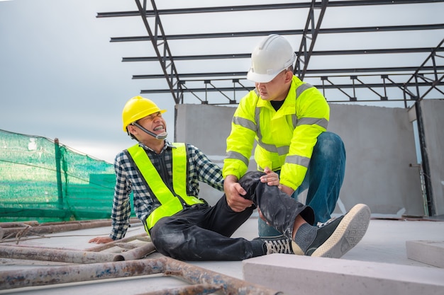 Foto pronto soccorso per emergenze infortuni nei cantieri. operaio edile è stato ferito in una caduta dall'alto in un cantiere edile. gli ingegneri aiutano il primo soccorso, il team di sicurezza aiuta i dipendenti in caso di incidente.