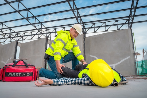 Foto pronto soccorso per emergenze infortuni nei cantieri. operaio edile è stato ferito in una caduta dall'alto in un cantiere edile. gli ingegneri aiutano il primo soccorso, il team di sicurezza aiuta i dipendenti in caso di incidente.