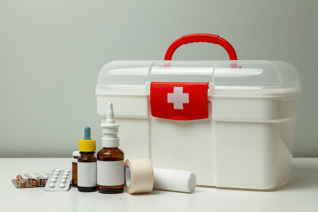 first aid kit white box with a cross and a red fastener and pills with medicine bottles