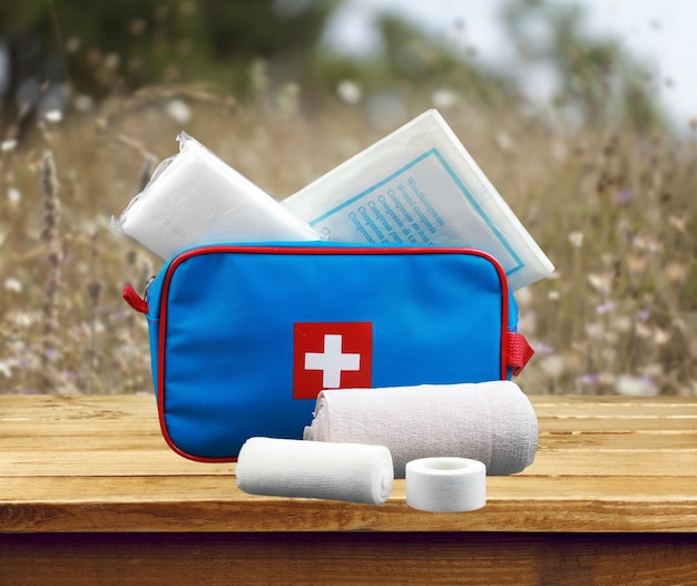 First aid kit with medical supplies on wooden background