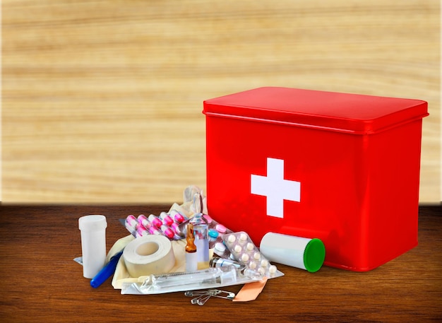 First aid kit with medical supplies on wooden table