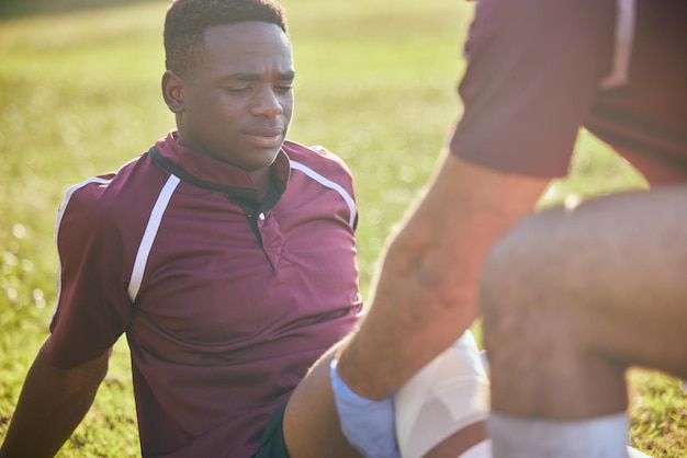 写真 応急処置スポーツ傷害とサッカー事故の黒人男性フィールドでのフィットネスとマッサージ運動による医療緊急事態との試合での膝痛のトレーニングトレーニングと理学療法