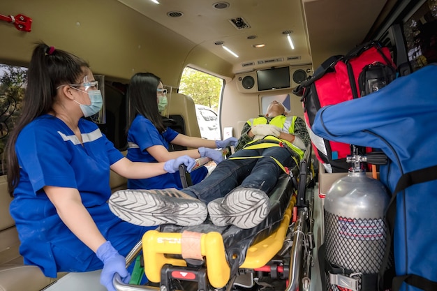 First aid training to transfer patient, loss of feeling or loss of normal movement. Paramedic team transfer man on ambulance stretcher into emergency car.