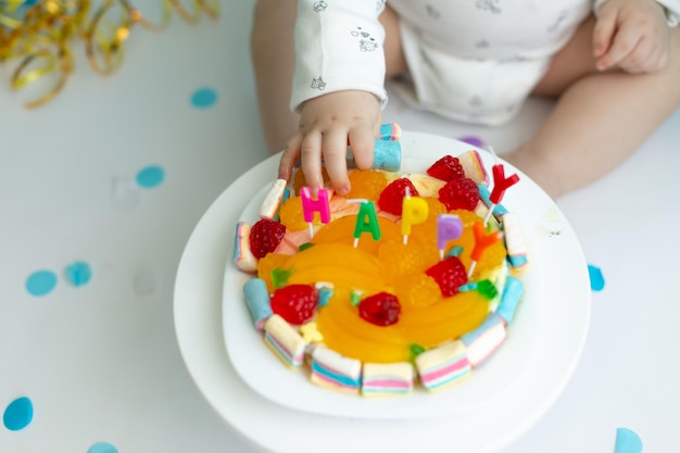 Foto la prima torta il bambino prende la torta con la mano. mano nella crema pasticcera. vacanza per bambini