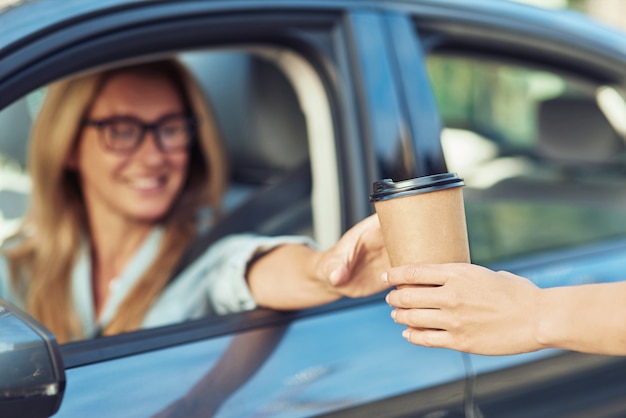 그러나 첫 번째 커피 행복한 백인 여성 사업가는 현대 자동차의 운전대 뒤에 앉아
