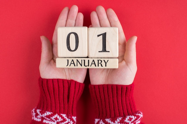 First day of happy new year concept. top above overhead close\
up view photo of female hands holding calender with the first of\
january isolated over bright color background