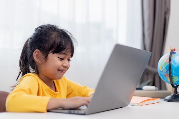 First day at school Asian little girl using a laptop computer studying through online elearning system