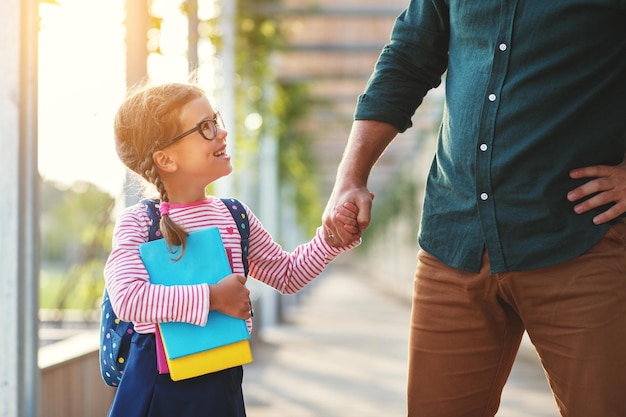 First day at school father leads a little child school girl in\
first grade