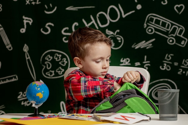 First day of school. Kid boy from primary school. Back to school. Little boy collects school backpack to school. Child from elementary school