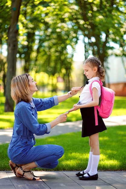 First day at school. mother leads a little child school girl in first grade