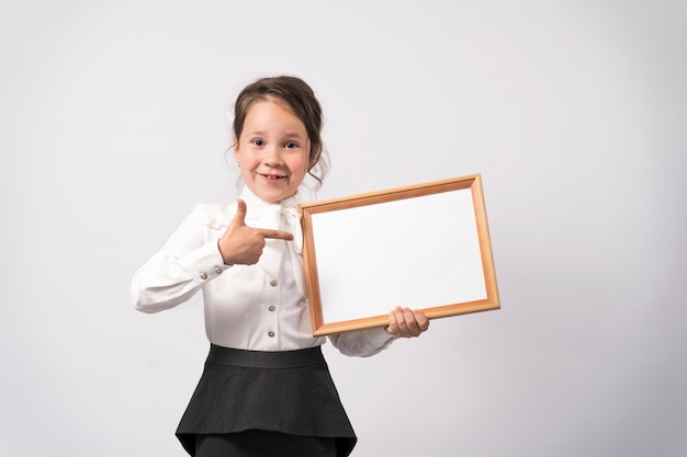 First grade school girl holds a white sheet for the inscription