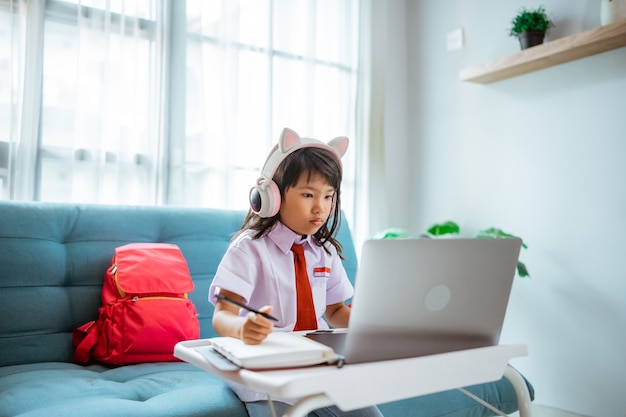 First grade school student with uniform during online class study with teacher at home