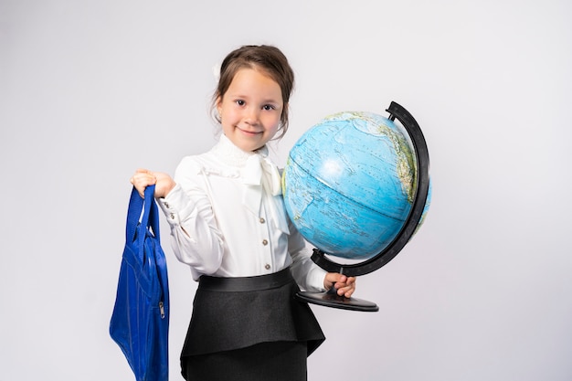 first grader holds a globe in one hand and a bag for training in the other