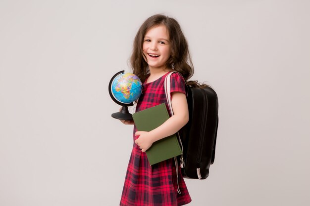 first-grader with books and a globe smiling 