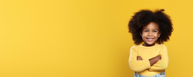 A first grader in a yellow jacket smiles and stands on a yellow background