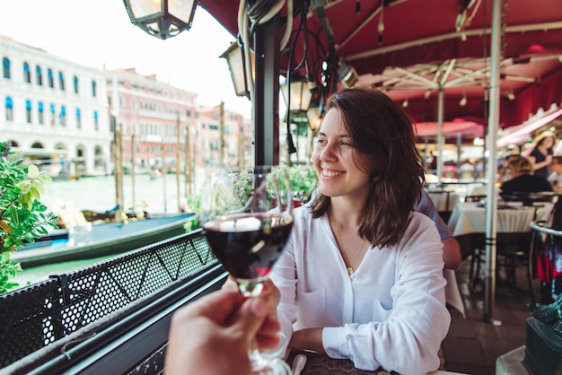 First person point of view couple in cafe outdoors drinking wine smiling woman grand canal venice