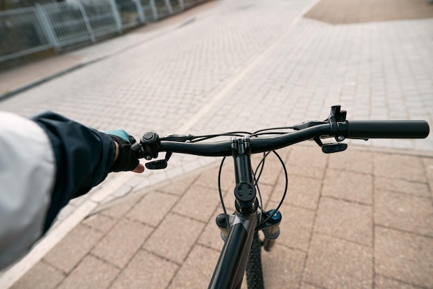 First person view of handling the bicycle on the empty asphalt road in the city towards sunlight Concept of using bicycle for commuting in the town