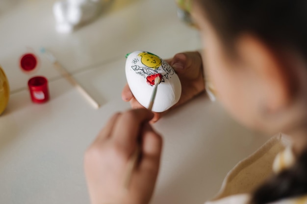 First person view of little girl painting easter egg