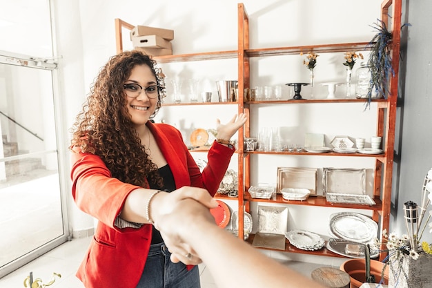 First person view van een vrouw die een klant begroet en ontmoet terwijl ze hem een rek met evenementartikelen laat zien