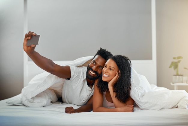 First selfie for the weekend Cropped shot of a young attractive couple taking a selfie in bed at home