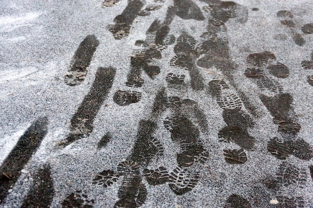 The first snow on the street. Many traces of people on the pavement.