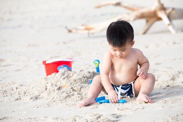 Il ragazzo di primo anno gioca con la sabbia, portando il bambino al concetto di spiaggia