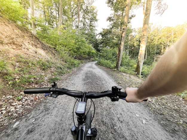 Firstperson view cycling in the forest closeup of a mountain\
bike handlebar summertime outdoor leisure sport activity\
concept