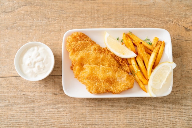 fish and chips - gebakken visfilet met chips en citroen op witte plaat