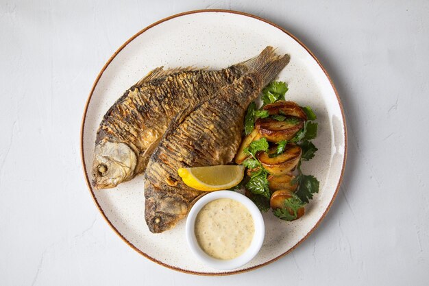 Fish as food and white plate with fried fish with potatoes a\
white plate is prepared as food